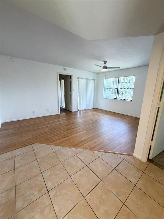 An open living area features light wood flooring, a ceiling fan, and sliding glass doors — 19505 QUESADA AVENUE UNIT U204, PORT CHARLOTTE, FL