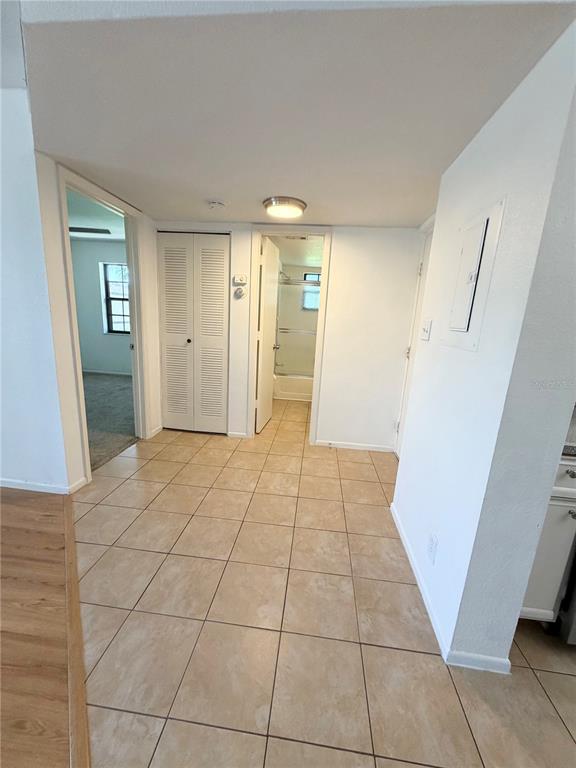 A tiled hallway leads to a bathroom and a bedroom with carpeted flooring — 19505 QUESADA AVENUE UNIT U204, PORT CHARLOTTE, FL
