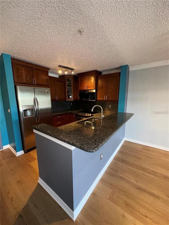A kitchen features dark wood cabinets, stainless steel appliances, and a granite-topped breakfast bar — 2400 FEATHER SOUND DRIVE UNIT 1435, CLEARWATER, FL