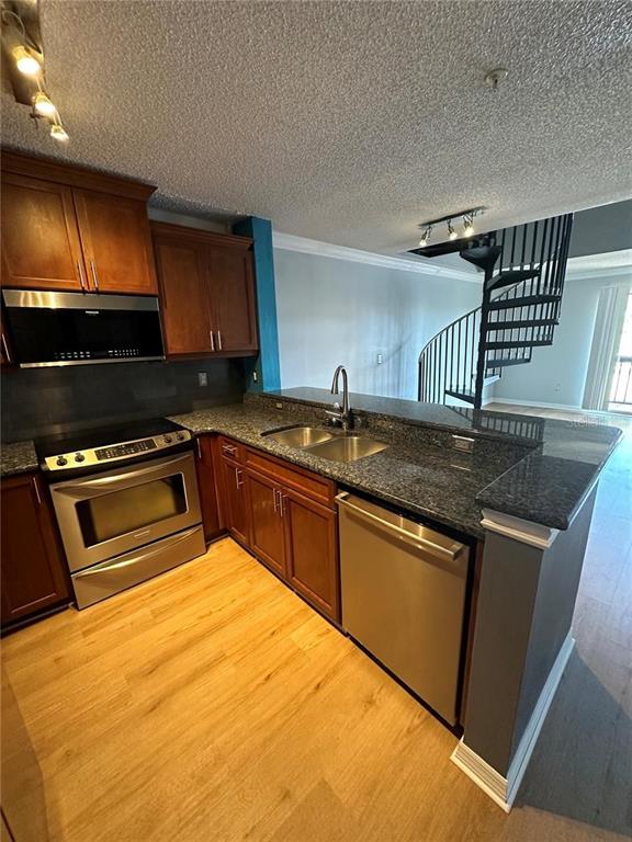 A kitchen features wood cabinets, granite countertops, stainless steel appliances, and a spiral staircase — 2400 FEATHER SOUND DRIVE UNIT 1435, CLEARWATER, FL