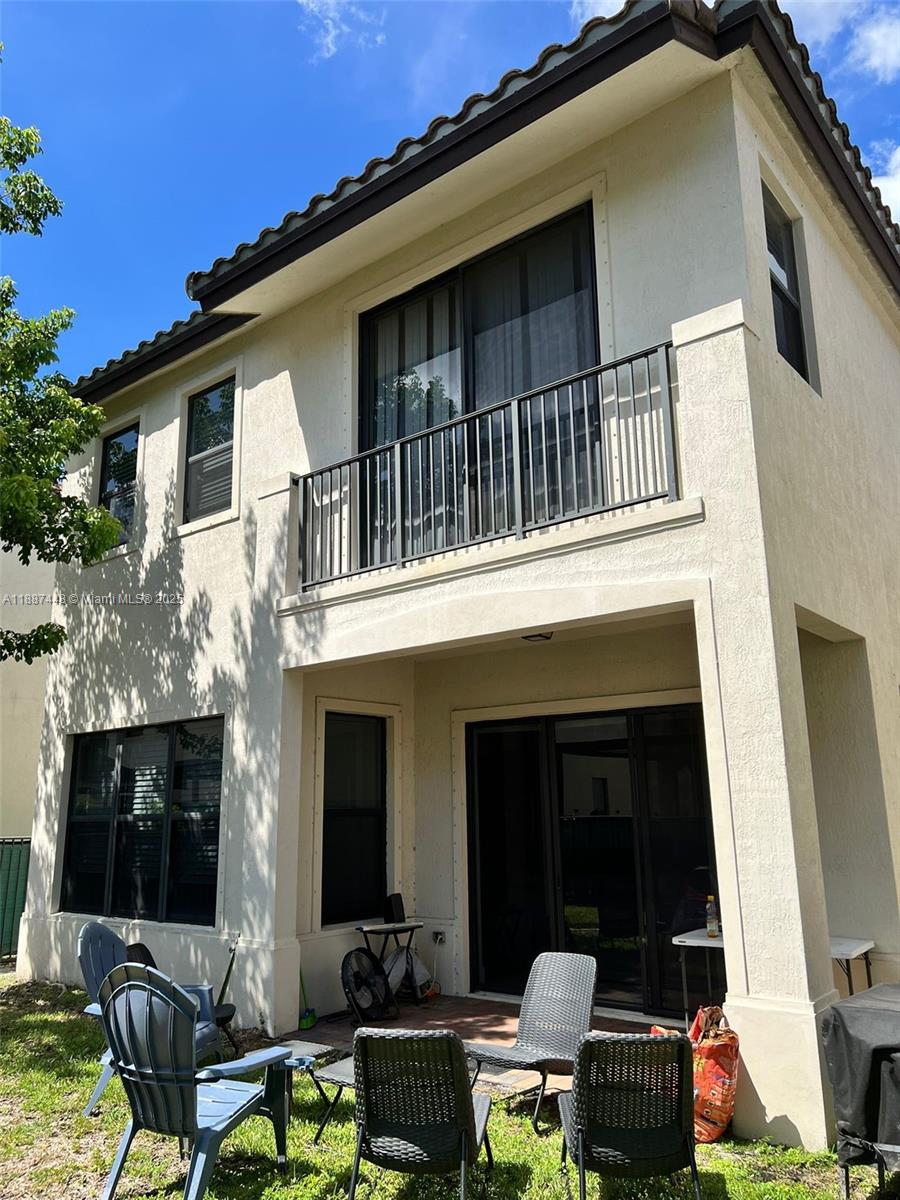 The exterior of a two-story stucco house features a balcony and a ground-level patio — 3214 W 97th St, Hialeah FL 33018, HIALEAH, FL