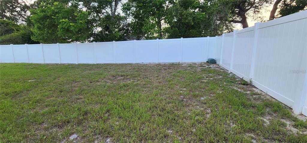 A grassy backyard features a white vinyl privacy fence along the perimeter — 2408 KIMBERLY DRIVE, DELTONA, FL