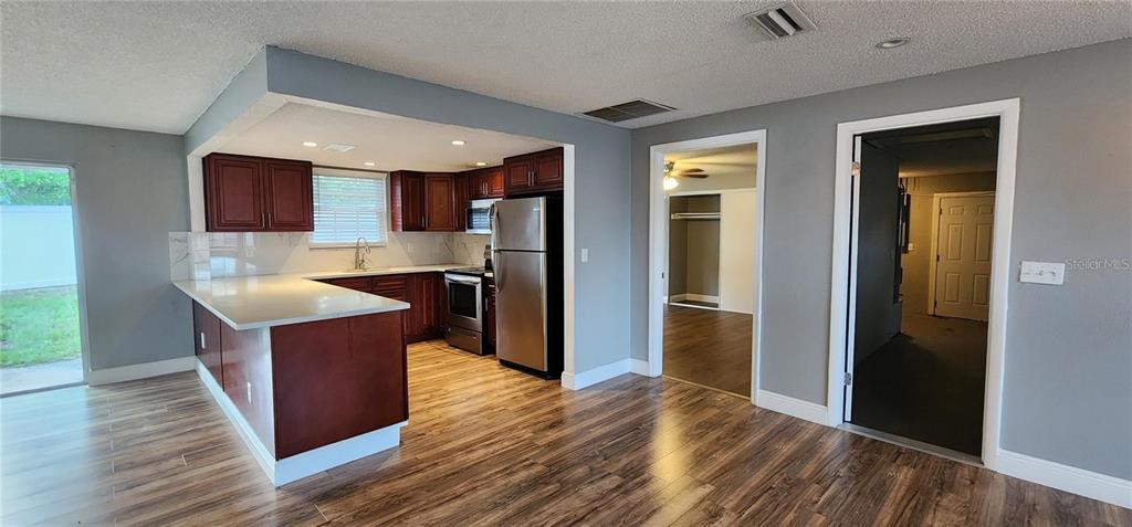 A kitchen with dark wood cabinets, stainless steel appliances, and a white countertop island — 2408 KIMBERLY DRIVE, DELTONA, FL