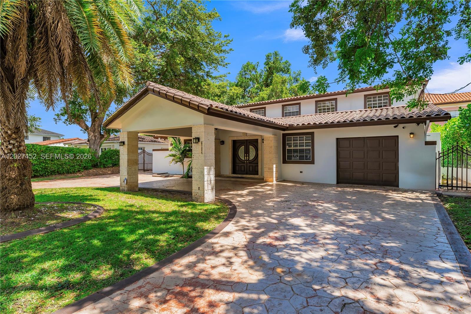 A two-story house with a stone-pillared porte-cochère, a brown garage door, and a tiled roof — 6284 SW 26th St, Miami FL 33155, MIAMI, FL