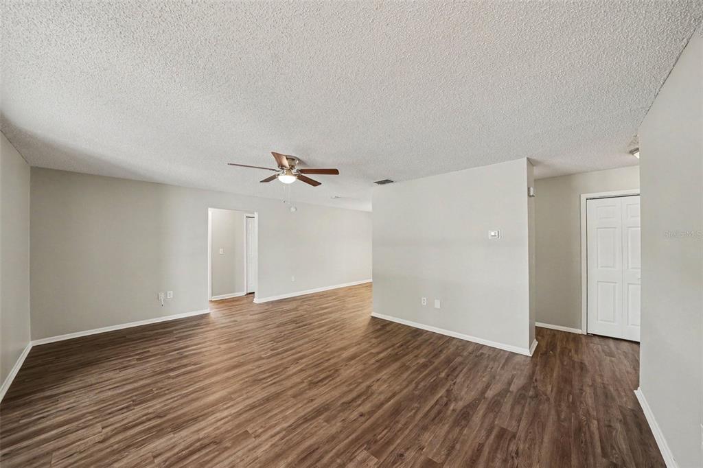 An empty living room features light gray walls, wood-look flooring, and a ceiling fan — 11424 SCALLOP DRIVE, PORT RICHEY, FL