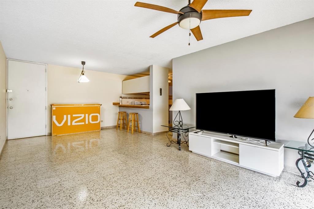 A living room features a ceiling fan, terrazzo flooring, a television, and a breakfast bar — 2 COND LAGUNA GARDENS II UNIT 9A, CAROLINA, PR
