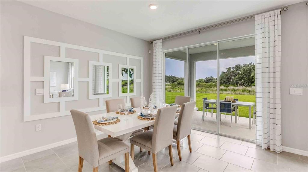 A dining room features a white table, upholstered chairs, wall molding, and sliding glass doors — 10503 FARM HILL AVENUE, LAND O LAKES, FL