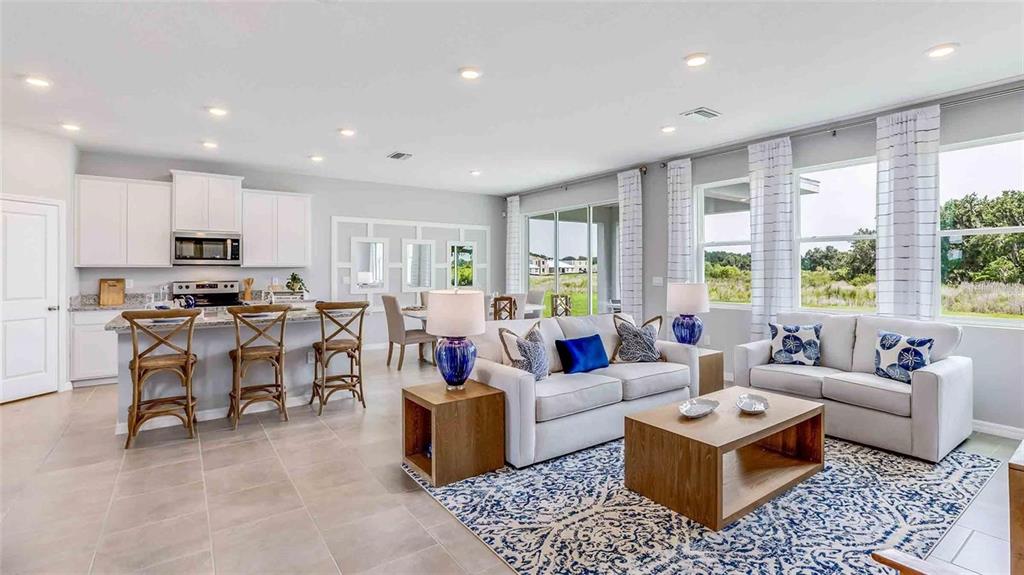 An open-concept living room and kitchen featuring light tile floors and neutral furniture — 10503 FARM HILL AVENUE, LAND O LAKES, FL