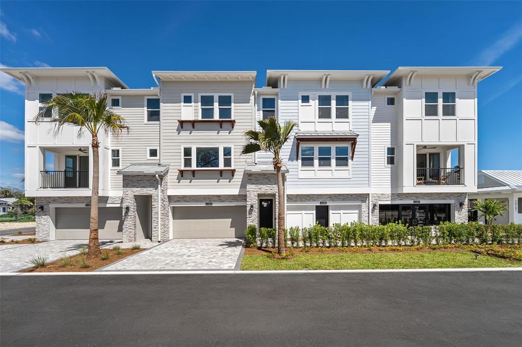 A multi-story residential building with light-colored siding, stone accents, and attached garages — 4105 TIDEWATCH LOOP, NEW SMYRNA BEACH, FL