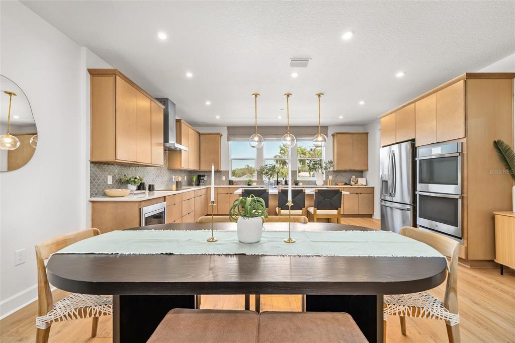 A dining area opens into a modern kitchen with light wood cabinetry and stainless appliances — 4105 TIDEWATCH LOOP, NEW SMYRNA BEACH, FL