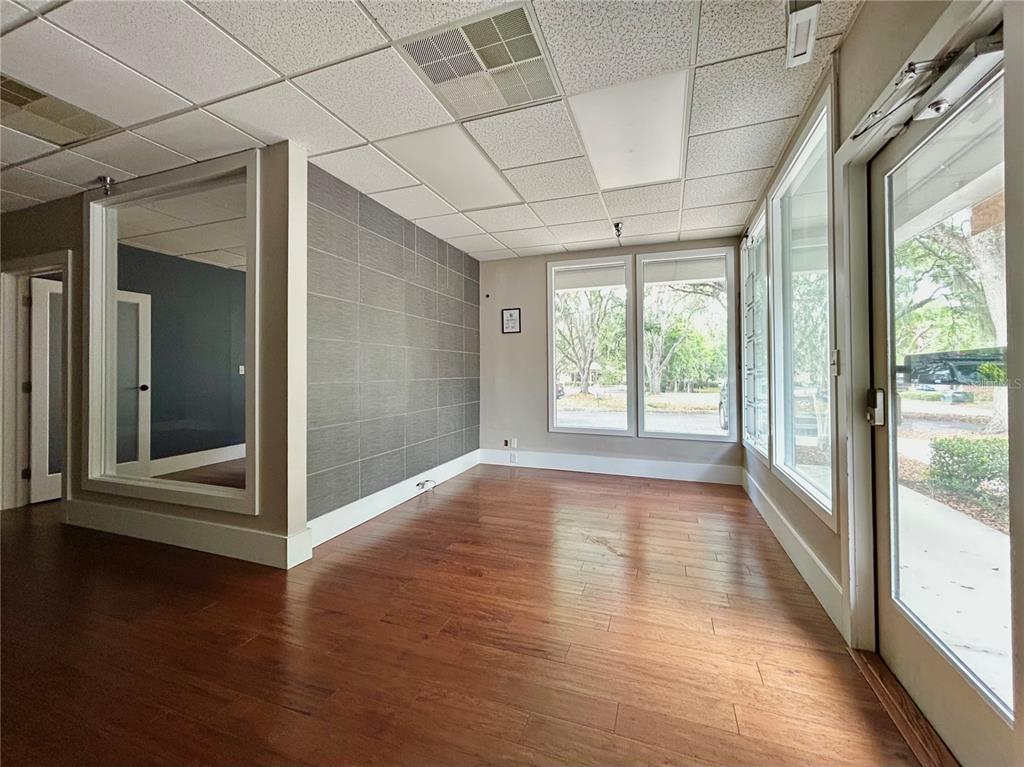 An office space with wood flooring, a gray tiled accent wall, and large glass windows — 2441 NW 43RD STREET UNIT 5B, GAINESVILLE, FL