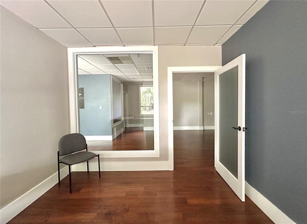 An office room features wood flooring, a large interior window, and an open doorway — 2441 NW 43RD STREET UNIT 5B, GAINESVILLE, FL