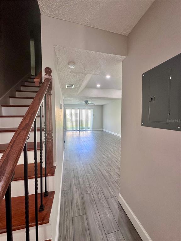 A view from a hallway looking toward a living area with wood-look flooring and stairs — 7512 BOLANOS COURT UNIT 7512, TAMPA, FL