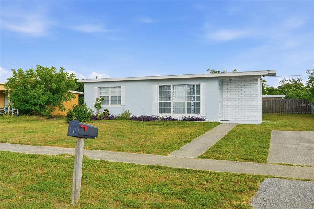 A light blue single-story house with a white brick accent wall and a front lawn — 21882 HAINES, PORT CHARLOTTE, FL