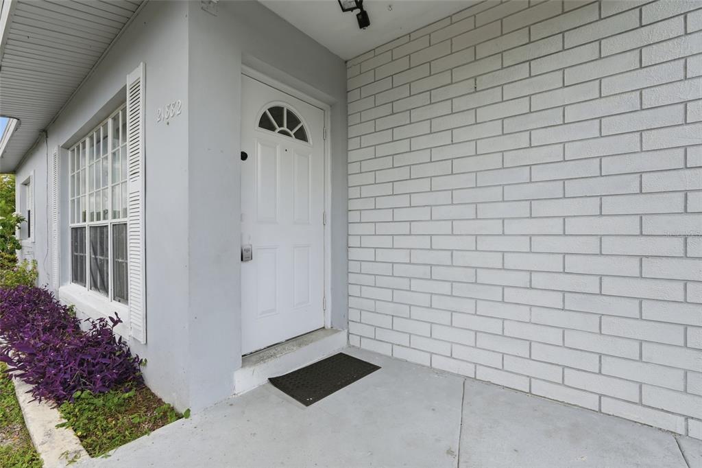 A white front door with a small window sits beside a painted brick wall — 21882 HAINES, PORT CHARLOTTE, FL