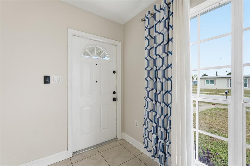 An entryway features a white front door, tiled flooring, and a window with patterned curtains — 21882 HAINES, PORT CHARLOTTE, FL
