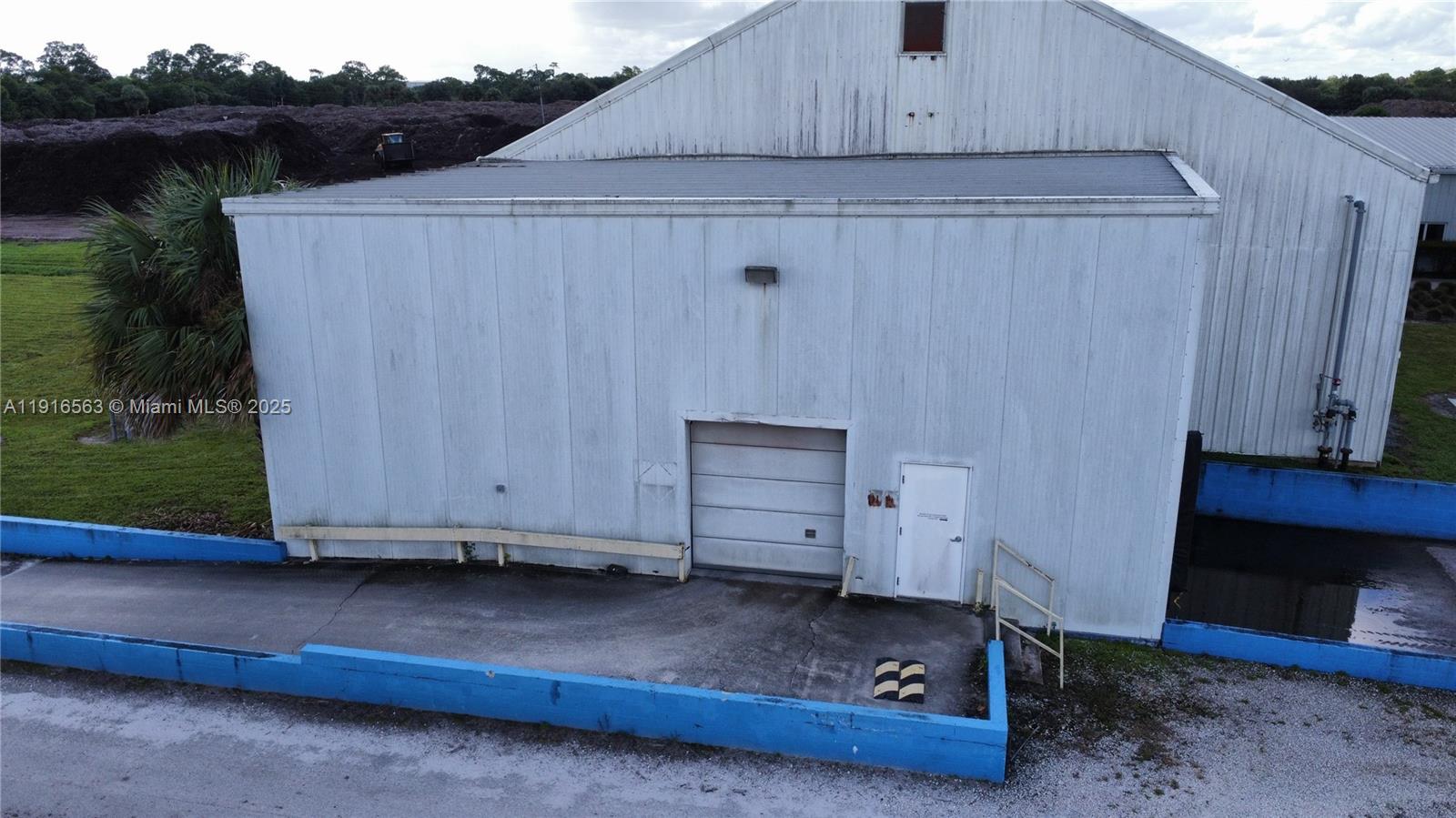 An exterior view of a white metal industrial building with a loading dock and ramp — 925 SW 74th Ave SW, FL 32968, FL
