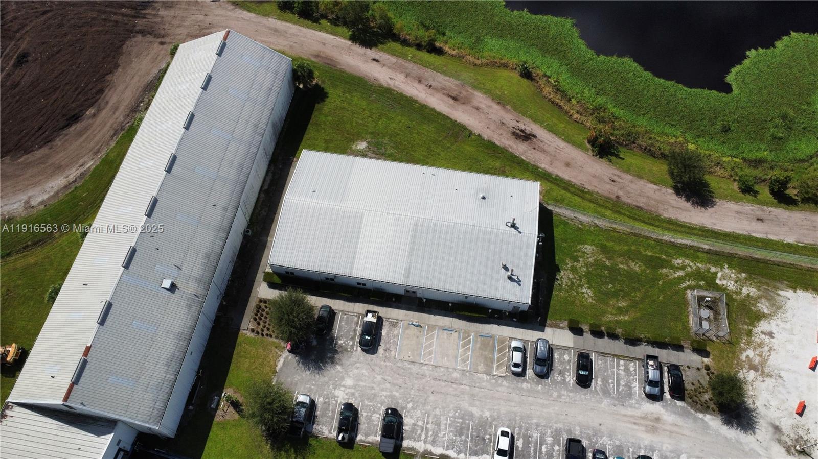 An aerial view shows two industrial warehouse buildings with adjacent parking lots and a pond — 925 SW 74th Ave SW, FL 32968, FL