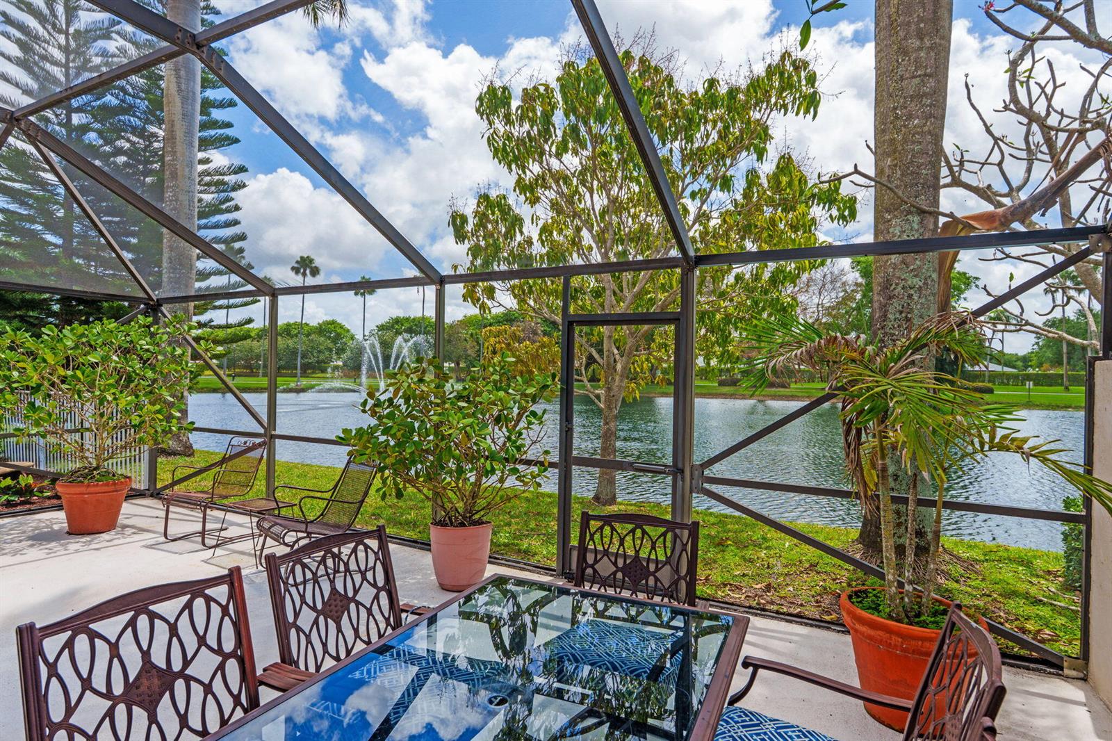 A screened-in patio overlooks a lake with a fountain and surrounding trees — 9722 Erica Court, Boca Raton FL 33496, BOCA RATON, FL