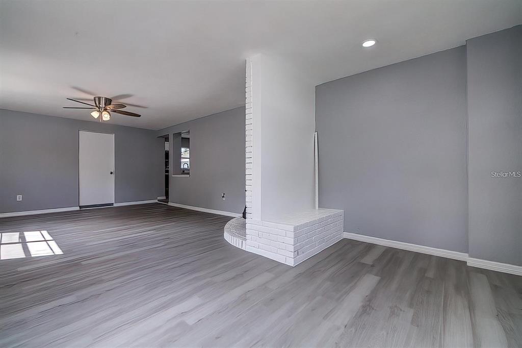 A living room features gray walls, wood-look flooring, and a central white brick fireplace — 2107 MONTICELLO AVENUE, LAKELAND, FL