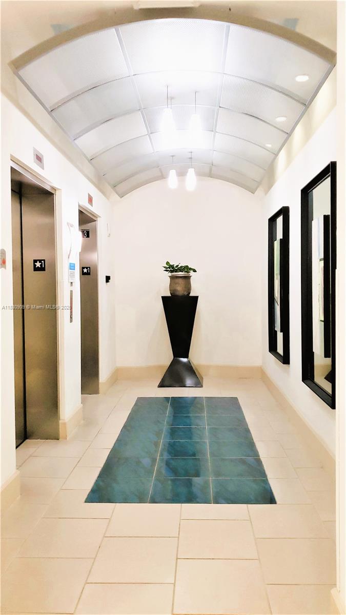 A hallway features two elevators, a central pedestal with a plant, and a tiled floor — 2000 N Bayshore Dr # 509, Miami FL 33137, MIAMI, FL