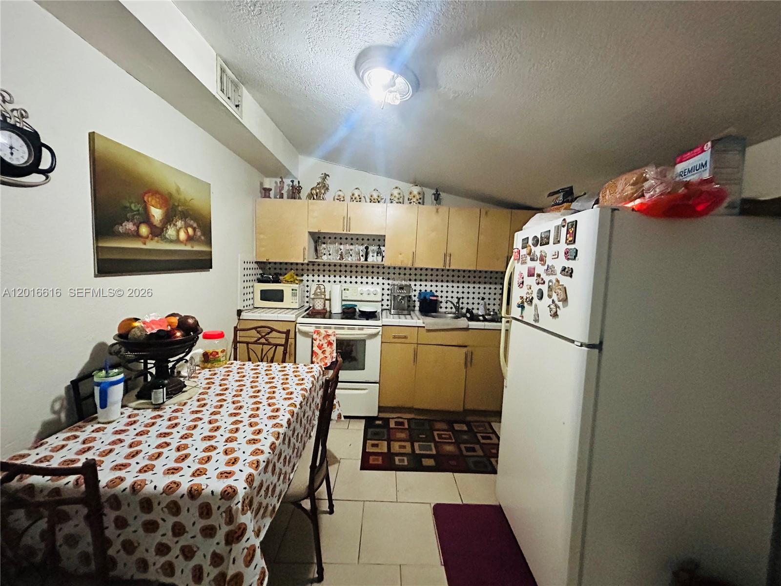 This kitchen features light wood cabinets, a patterned backsplash, and a dining table — 244 SW 36th Ave, Miami FL 33135, MIAMI, FL