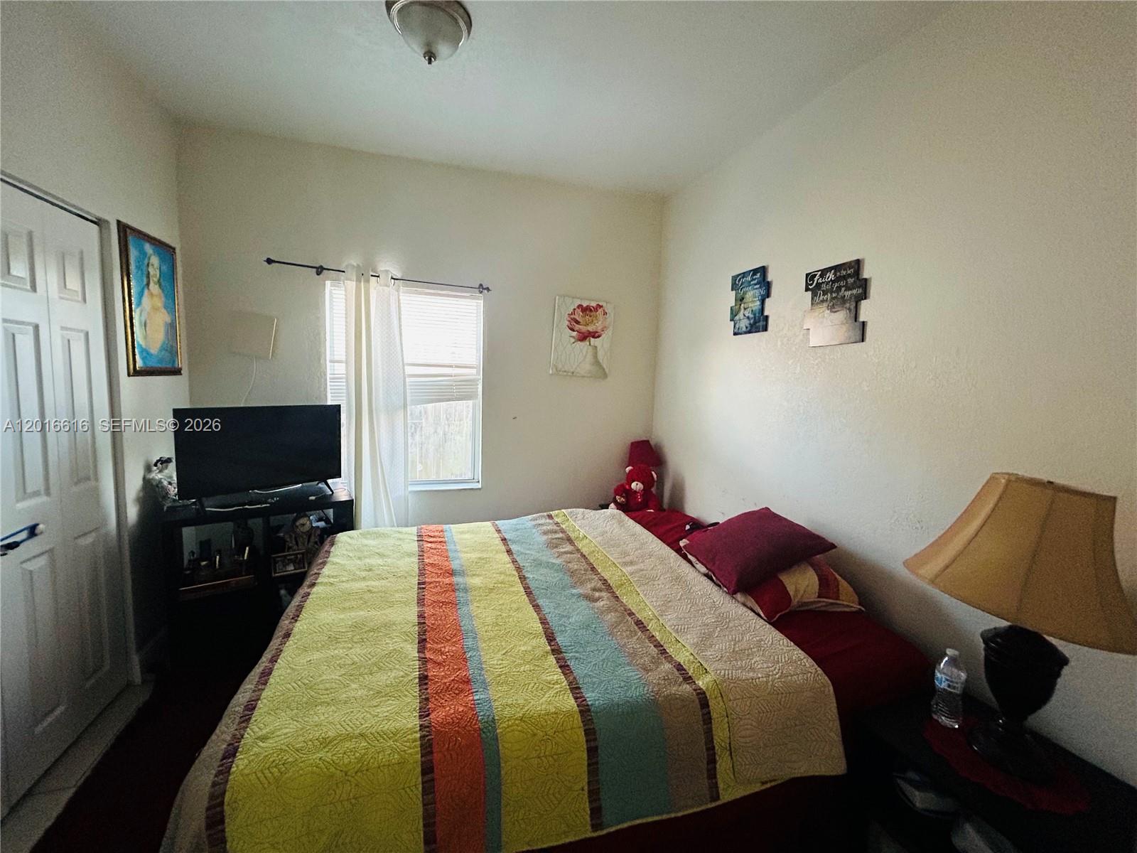 A bedroom features a bed with a striped quilt, a television, and wall decor — 244 SW 36th Ave, Miami FL 33135, MIAMI, FL