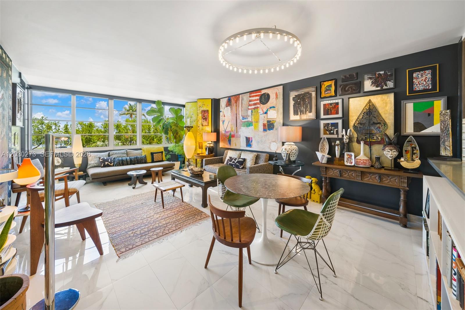 A bright living and dining area features dark accent walls, eclectic art, and marble floors — 1670 Lincoln Ct # 2B, Miami Beach FL 33139, MIAMI BEACH, FL