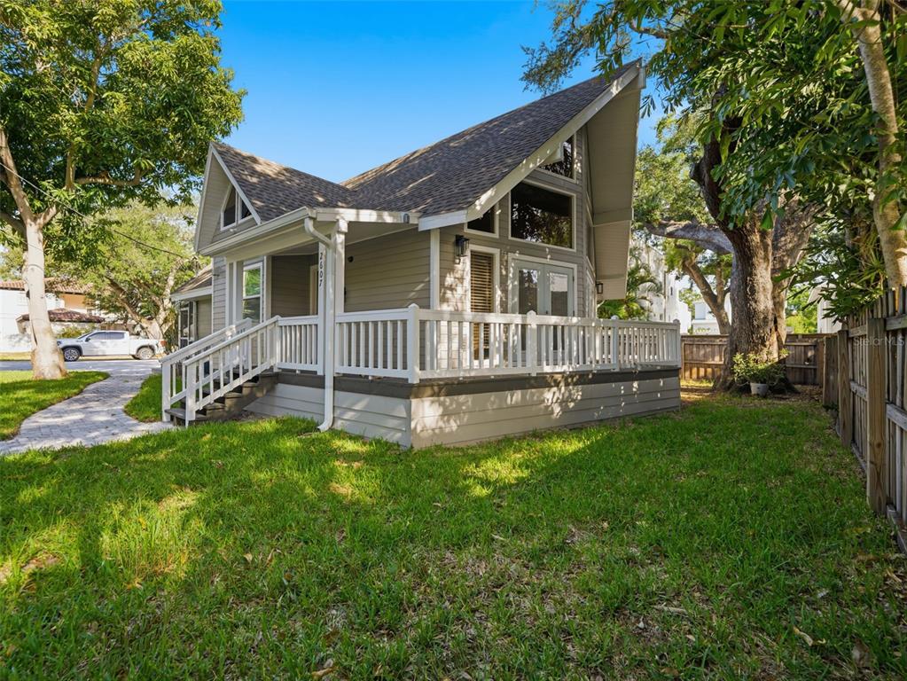 A light-colored house with a steep roof and a large wraparound deck in a yard — 2607 W WYOMING AVENUE, TAMPA, FL