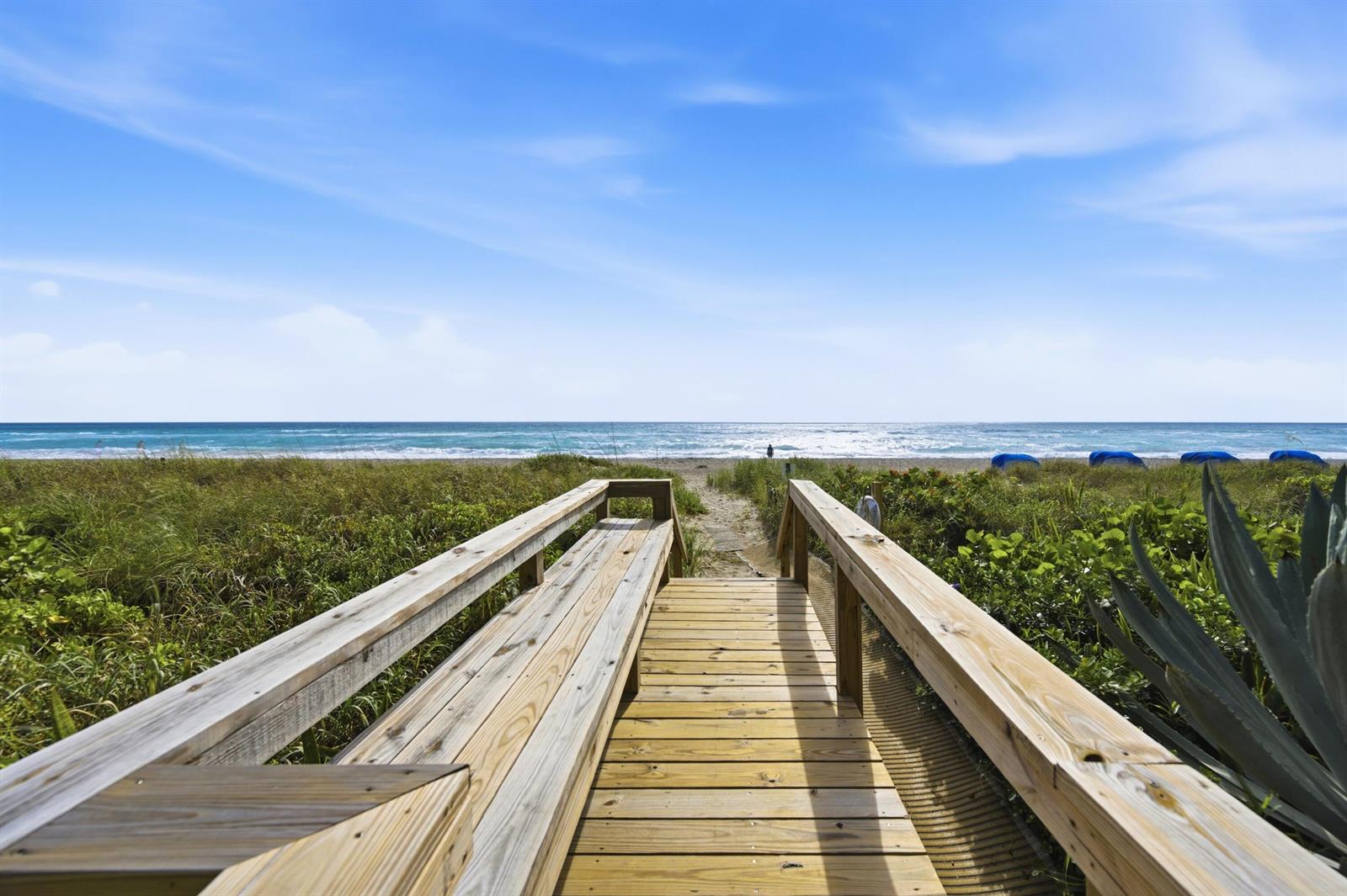 A wooden boardwalk with built-in bench seating leads toward a sandy beach and the ocean — 2778 S Ocean Boulevard # 206s, Palm Beach FL 33480, PALM BEACH, FL
