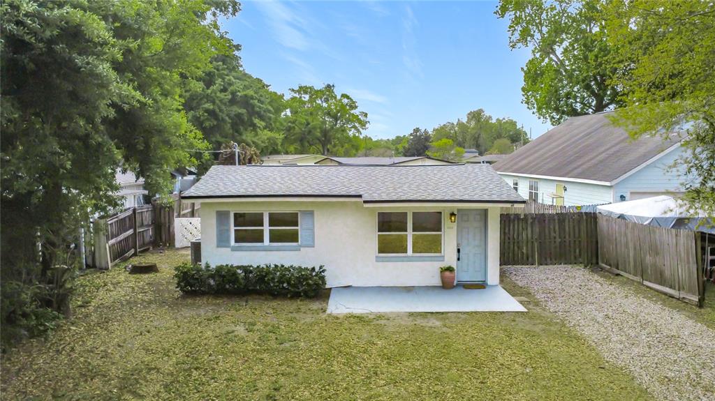 A single-story white house with a gray roof, blue shutters, and a gravel driveway — 1018 DOWD AVENUE, ORLANDO, FL