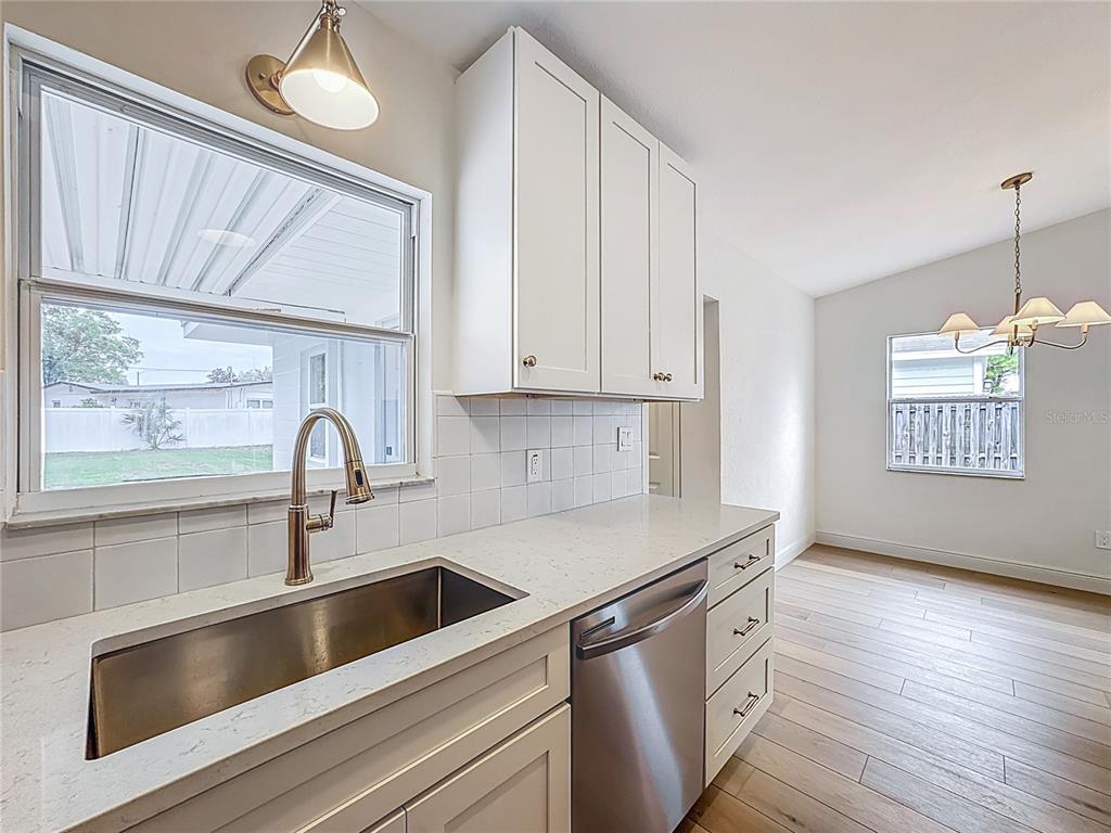 A kitchen features white cabinets, quartz countertops, a stainless steel sink, and a dishwasher — 1018 DOWD AVENUE, ORLANDO, FL