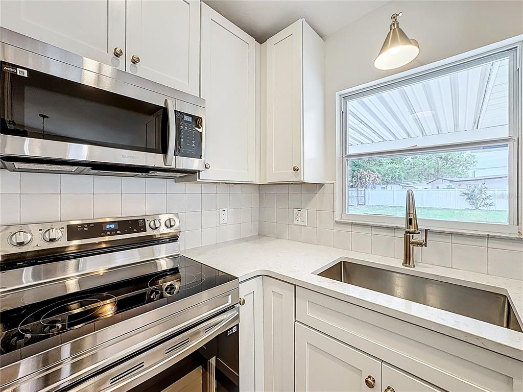 A kitchen features white cabinets, a stainless steel microwave and stove, and a sink — 1018 DOWD AVENUE, ORLANDO, FL