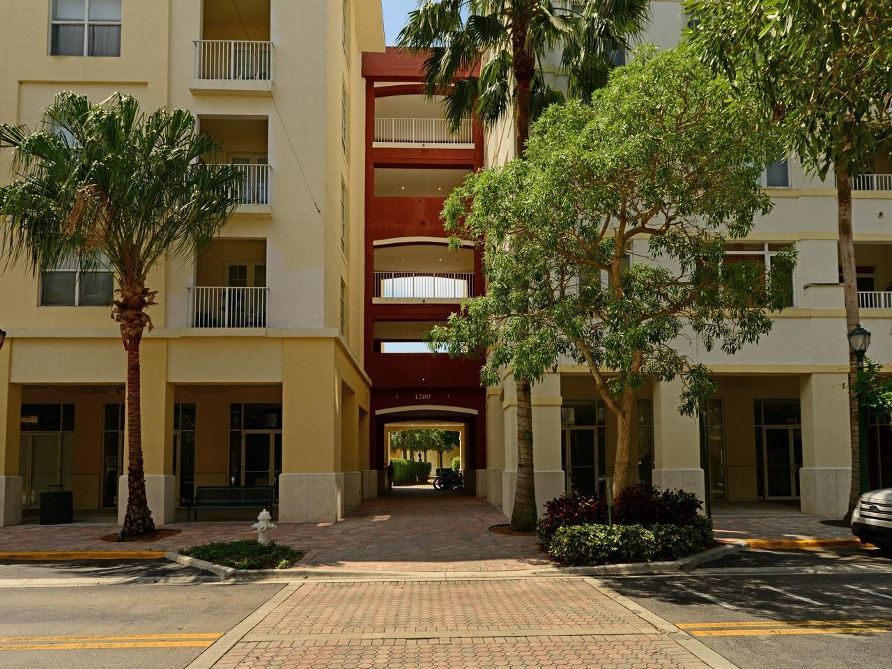 A view of a multi-story apartment building with a red central breezeway and palm trees — 1200 Town Center Drive # 216, Jupiter FL 33458, JUPITER, FL