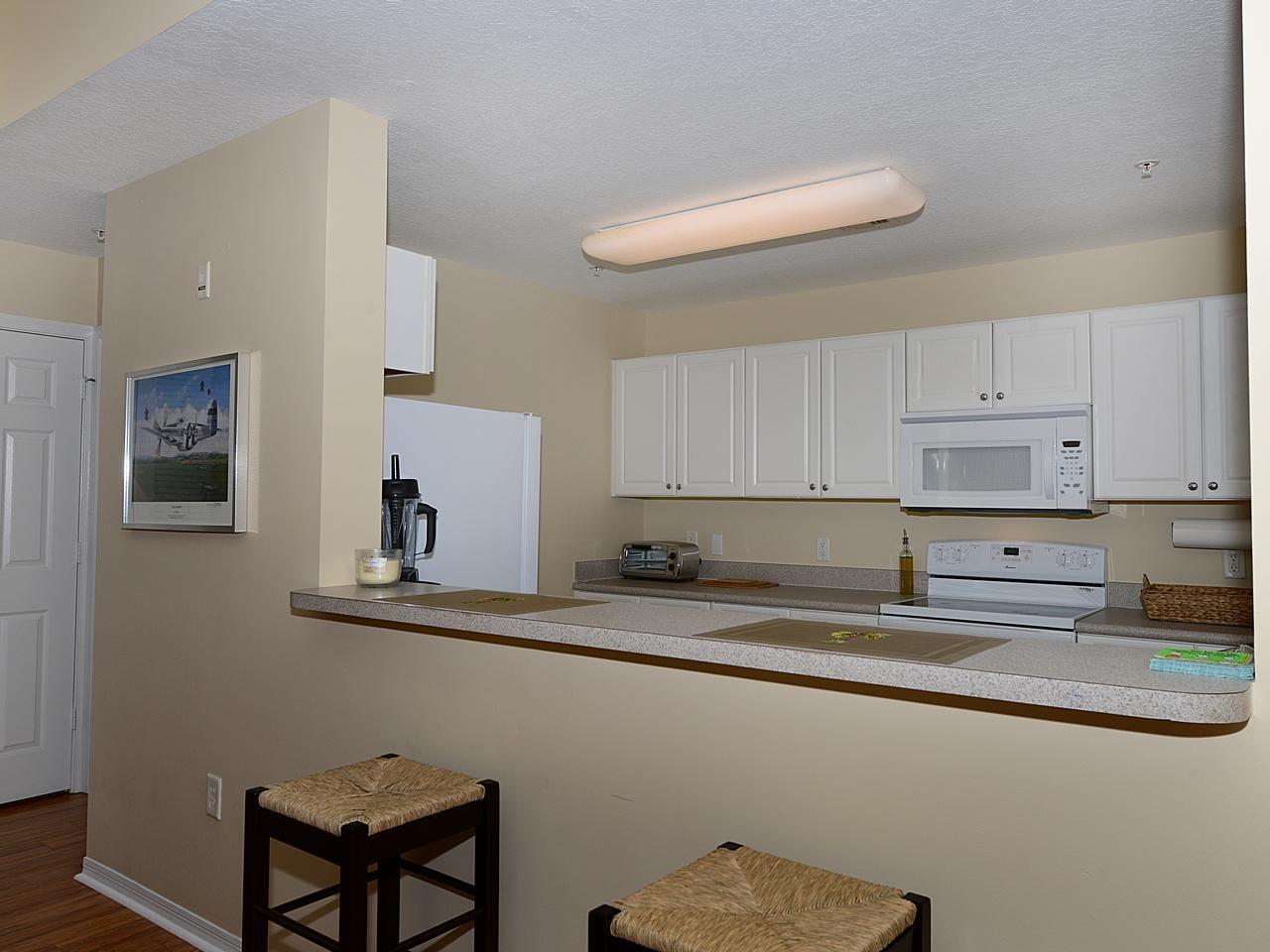 A kitchen with white cabinets, a breakfast bar, and a white stove and microwave — 1200 Town Center Drive # 216, Jupiter FL 33458, JUPITER, FL