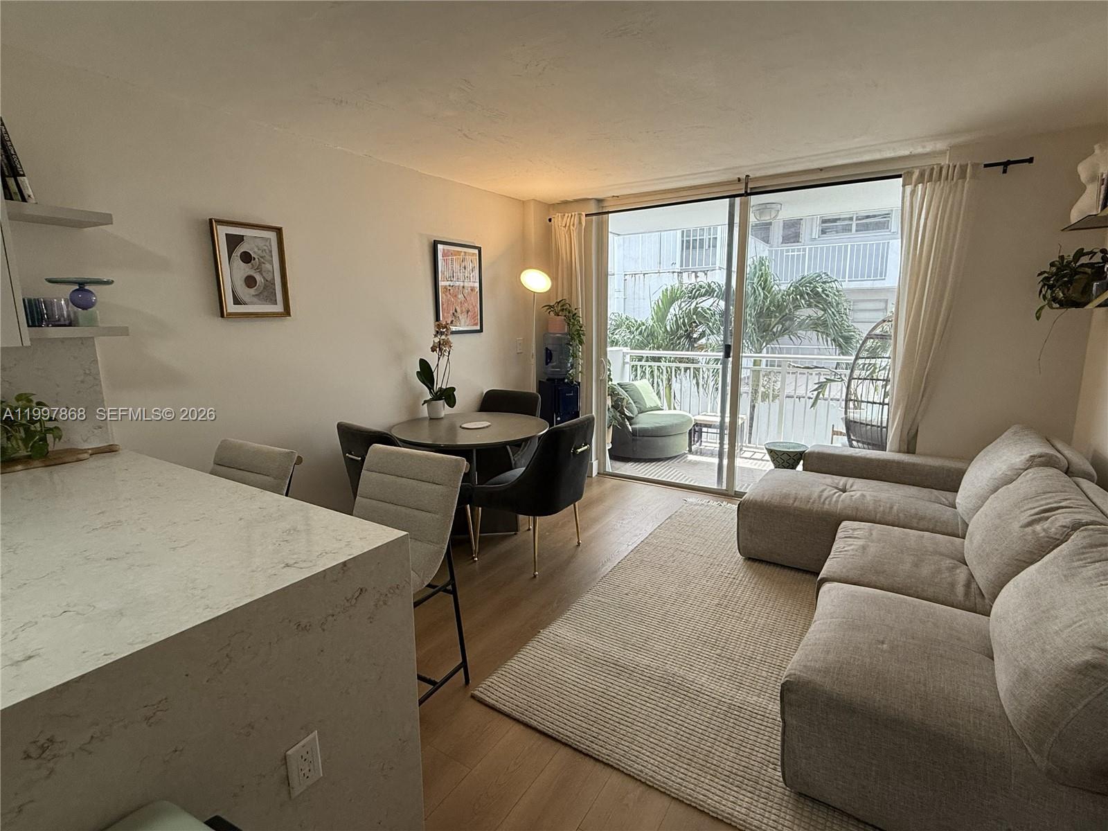 A living and dining area features a sectional sofa, a round table, and a balcony — 1666 West Ave # 305, Miami Beach FL 33139, MIAMI BEACH, FL