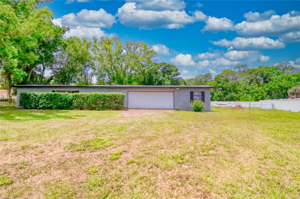 A gray, single-story house with a two-car garage sits on a large, grassy lot — 5205 FIVE ACRE ROAD, PLANT CITY, FL