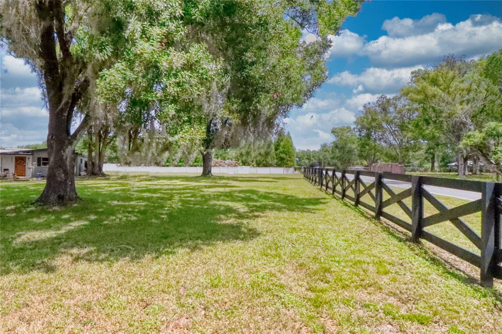 A grassy yard features large trees with Spanish moss and a black wooden fence — 5205 FIVE ACRE ROAD, PLANT CITY, FL