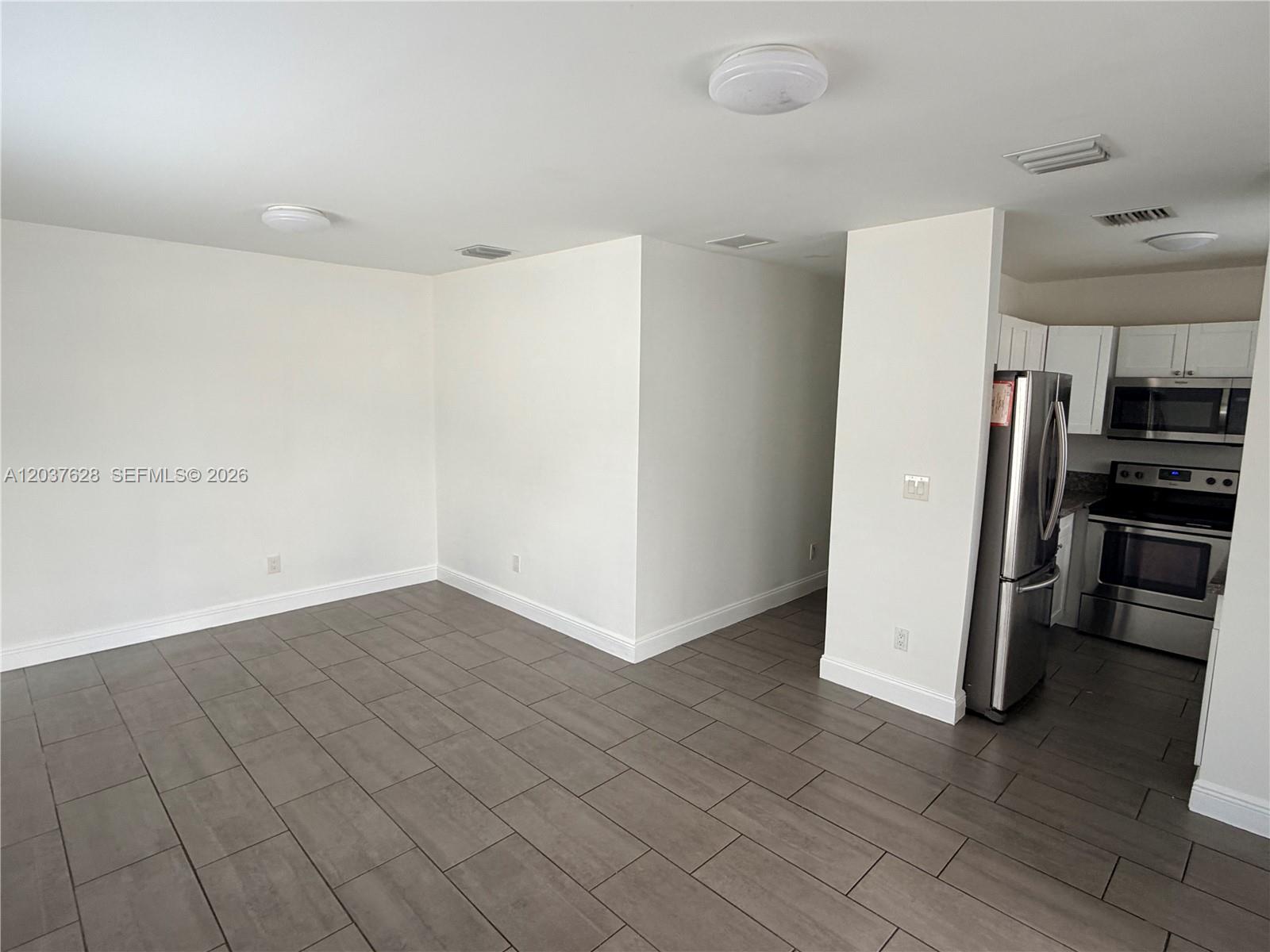 An open-concept living area features gray tile flooring and an adjacent kitchen with stainless appliances — 1315 N 22nd Ave # A2, Hollywood FL 33020, HOLLYWOOD, FL