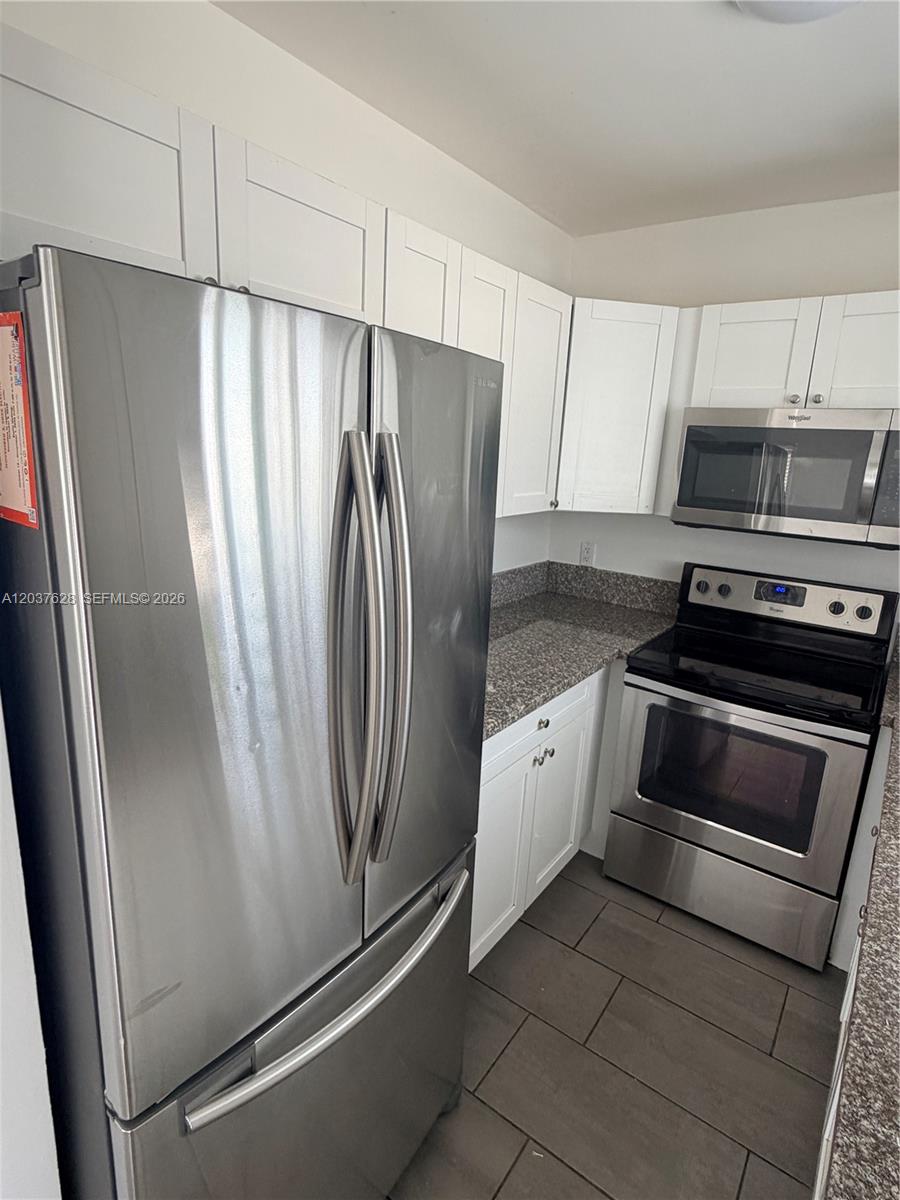 A kitchen features stainless steel appliances, white cabinets, and granite countertops over tile flooring — 1315 N 22nd Ave # A2, Hollywood FL 33020, HOLLYWOOD, FL