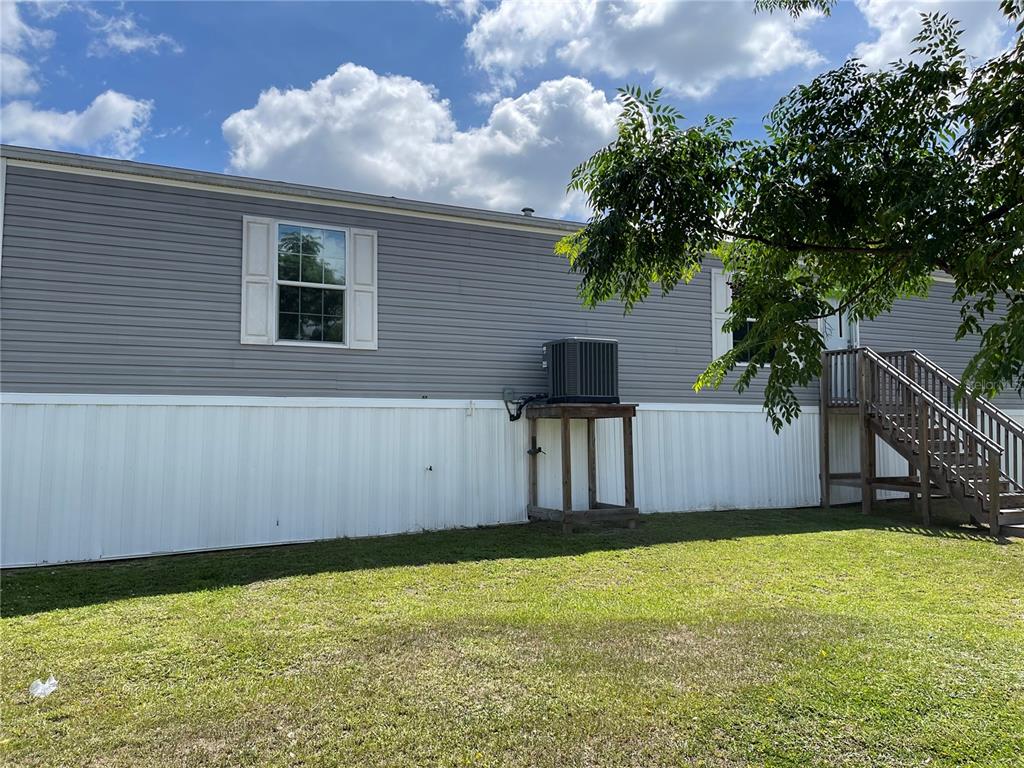 Exterior view of a gray manufactured home with a raised air conditioning unit and stairs — 6964 POMPEII ROAD, ORLANDO, FL