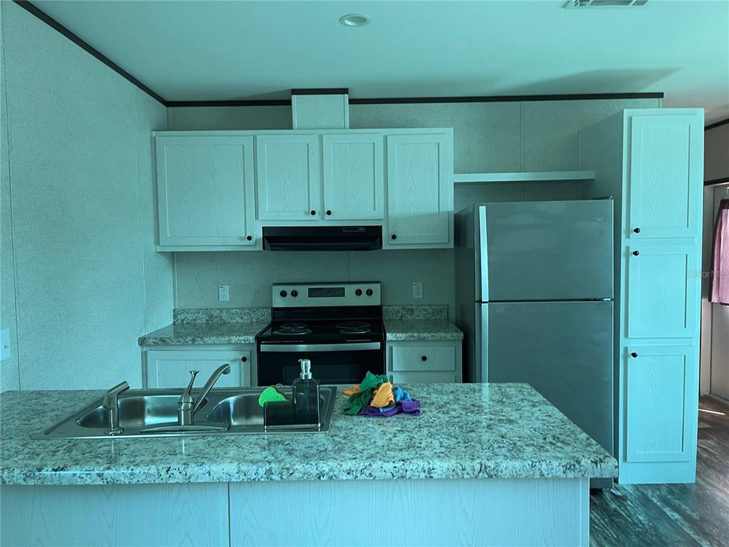 A kitchen features light blue cabinets, speckled countertops, a stainless steel refrigerator, and a sink — 6964 POMPEII ROAD, ORLANDO, FL