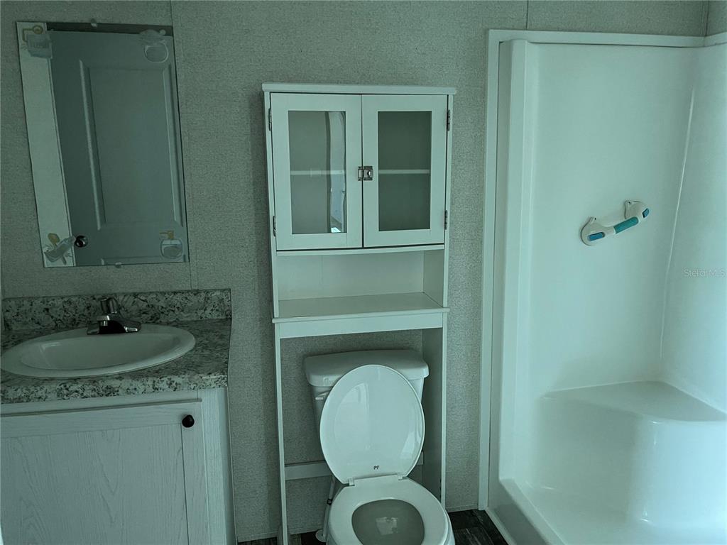 A bathroom features a vanity with a sink, a toilet with storage, and a shower — 6964 POMPEII ROAD, ORLANDO, FL