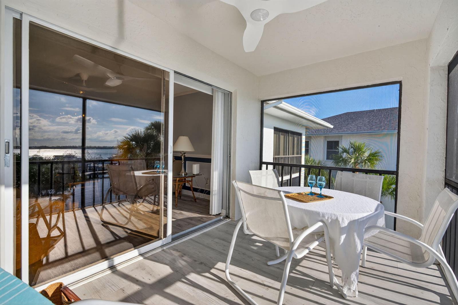 A screened-in balcony features a dining set, light wood-look flooring, and views of the water — 390 NE Edgewater Drive # 403, Stuart FL 34996, STUART, FL