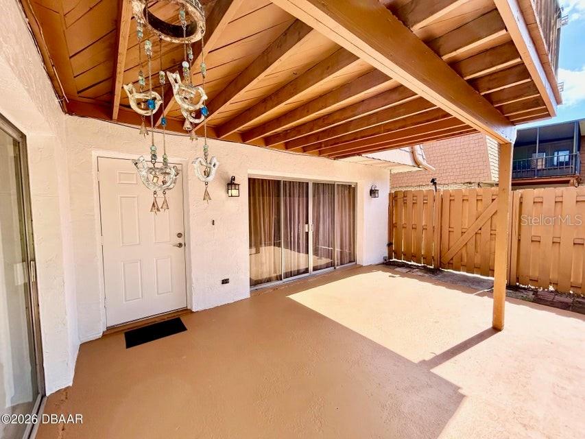 A covered patio features a white door, sliding glass doors, and a wooden ceiling — 122 MOONSTONE COURT, PORT ORANGE, FL