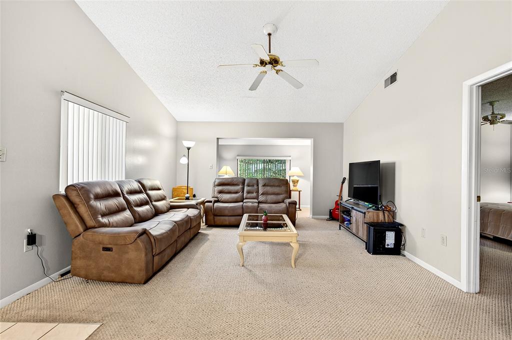 A living room features brown leather reclining furniture, a coffee table, and a television console — 2945 SW 32ND AVENUE UNIT D6, OCALA, FL