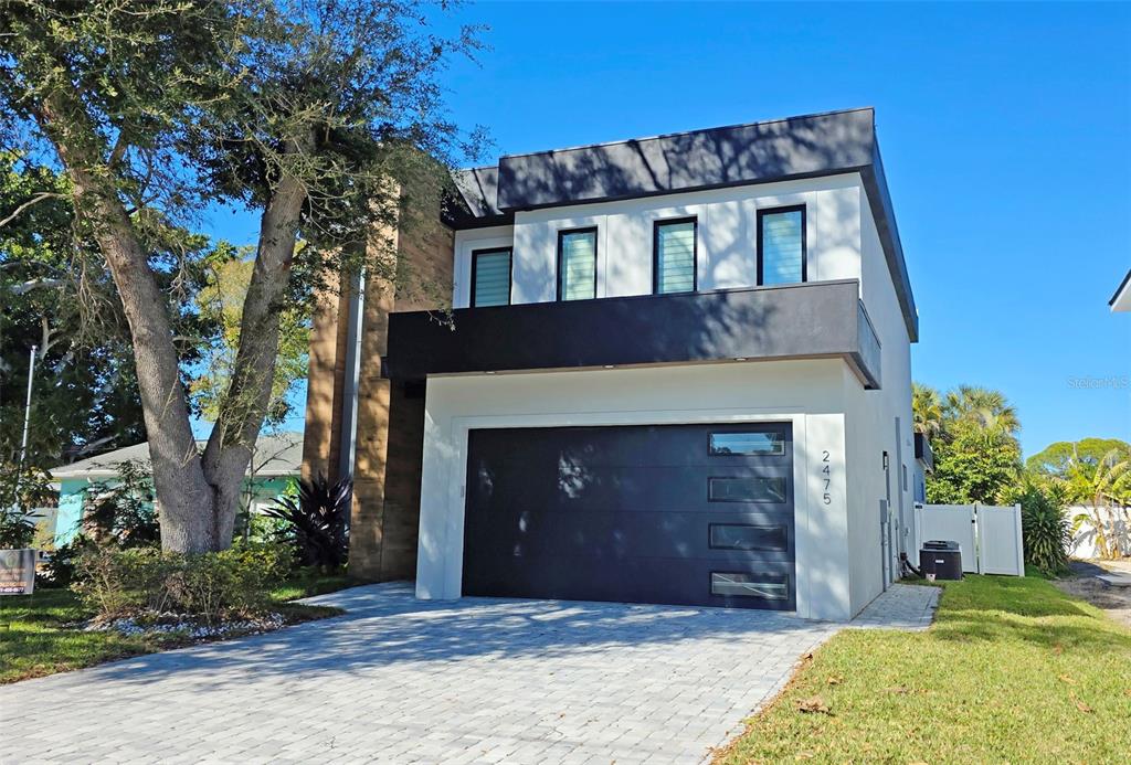 A modern two-story house with a dark garage door and a stone-accented side wall — 2475 BAY STREET, SARASOTA, FL