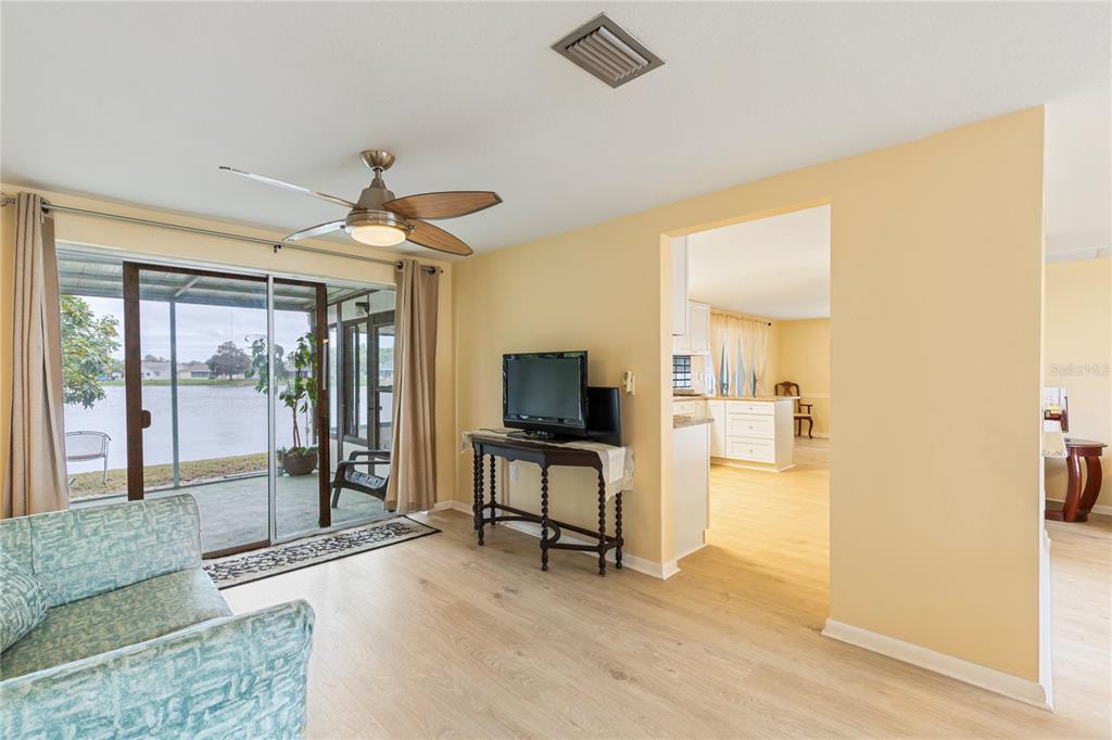 A living room with light wood flooring, a ceiling fan, and sliding doors to a patio — 3228 ROCK VALLEY DRIVE, HOLIDAY, FL