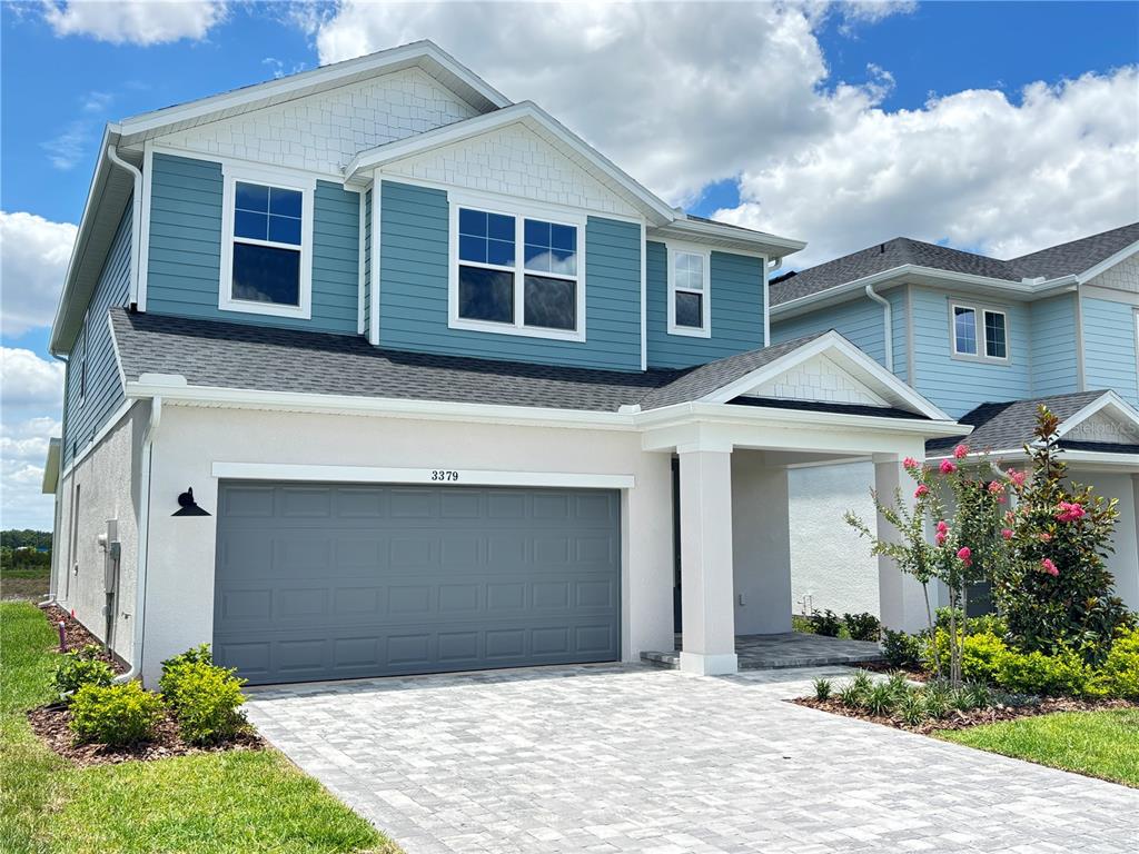 A two-story house with blue siding, a gray garage door, and a paved driveway — 3379 YELLOW CASSIA DRIVE, WESLEY CHAPEL, FL