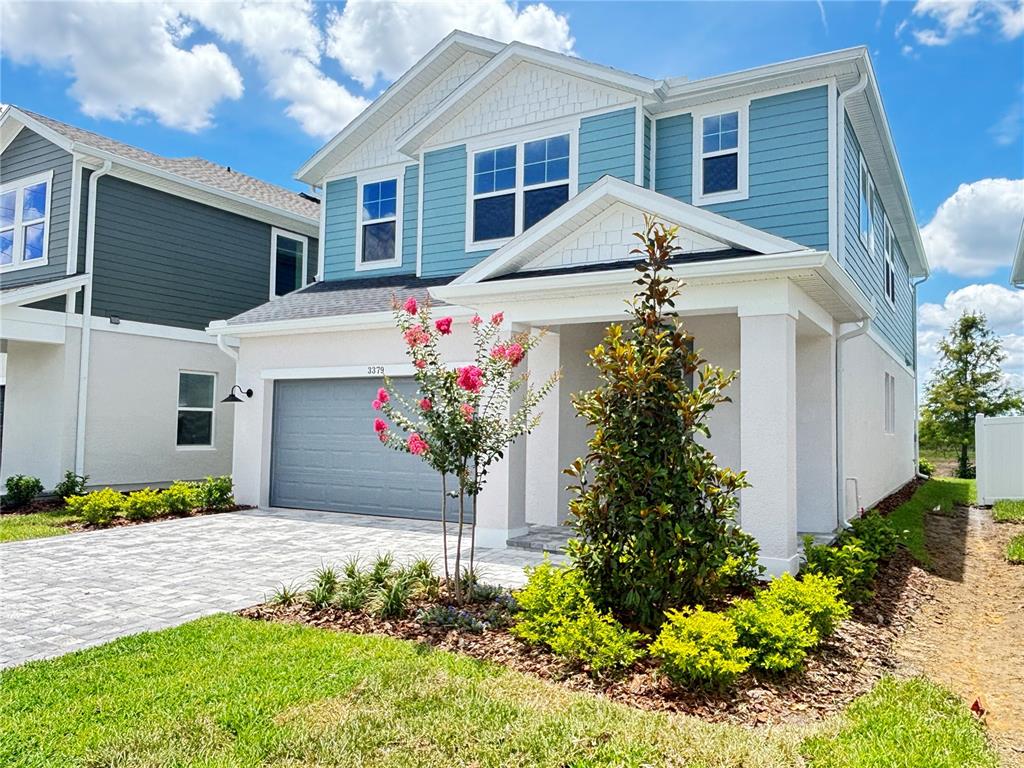 A two-story house with blue siding, a white stucco base, and a paved driveway — 3379 YELLOW CASSIA DRIVE, WESLEY CHAPEL, FL
